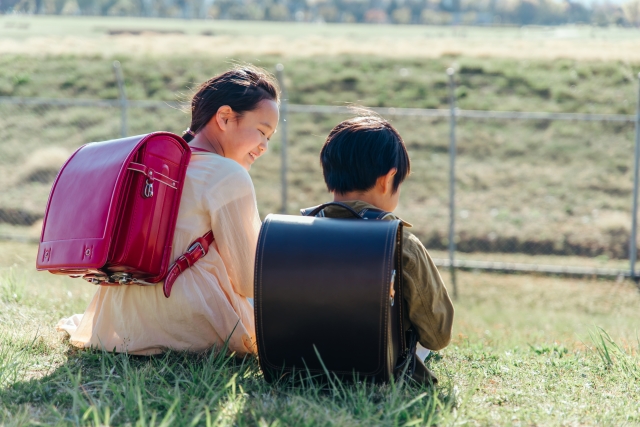 小学生の姉と弟が土手で話す様子