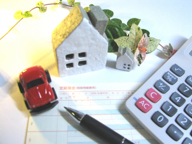 電卓、通帳と模型の家と車の画像